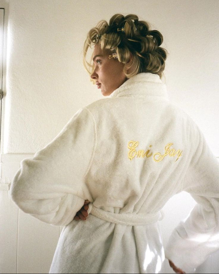 Person wearing a white robe with 'Elvis Jerry' branding in a bathroom setting.